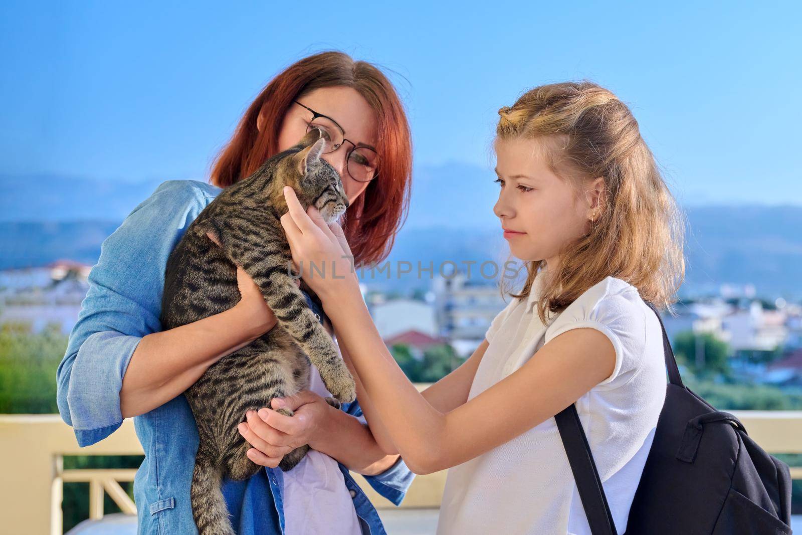 Mom preteen daughter and cat pet together on the porch of the house. Family, lifestyle, pets concept