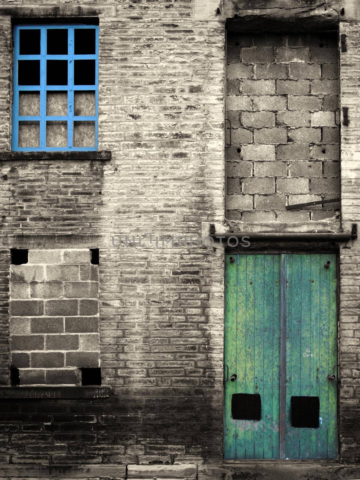 vintage style colorized image of an abandoned industrial warehouse and factory building with blue windows and green door by philopenshaw