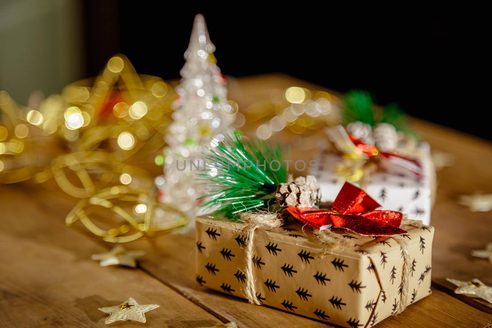 Christmas new year boxes with surprise and red bow. Yellow garland, lights in a dark room.