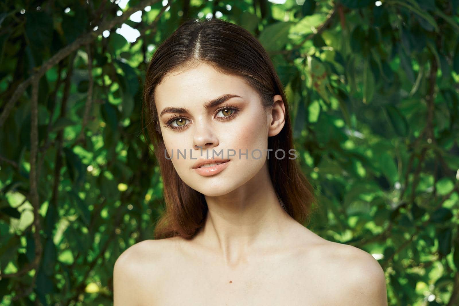 smiling woman attractive look bare shoulders green leaves close-up. High quality photo
