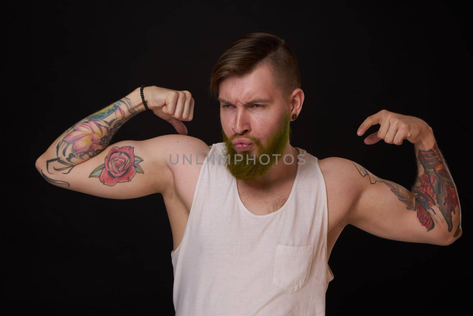 bearded man with tattoos on his arms gesturing with his hands dark background. High quality photo