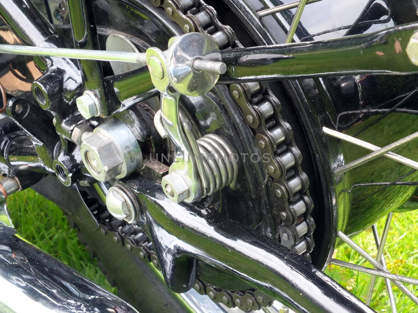 close up of the rear wheel and drive chain of a black vintage motorcycle