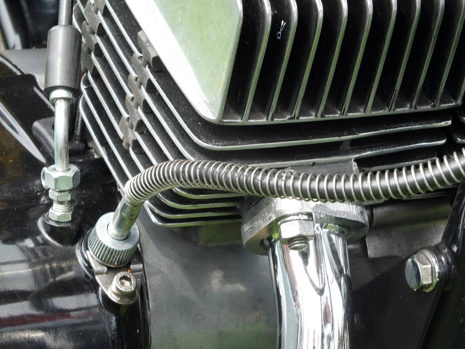 close up of the engine block of a vintage black motorcycle with shiny metal cylinder head and chrome pipes
