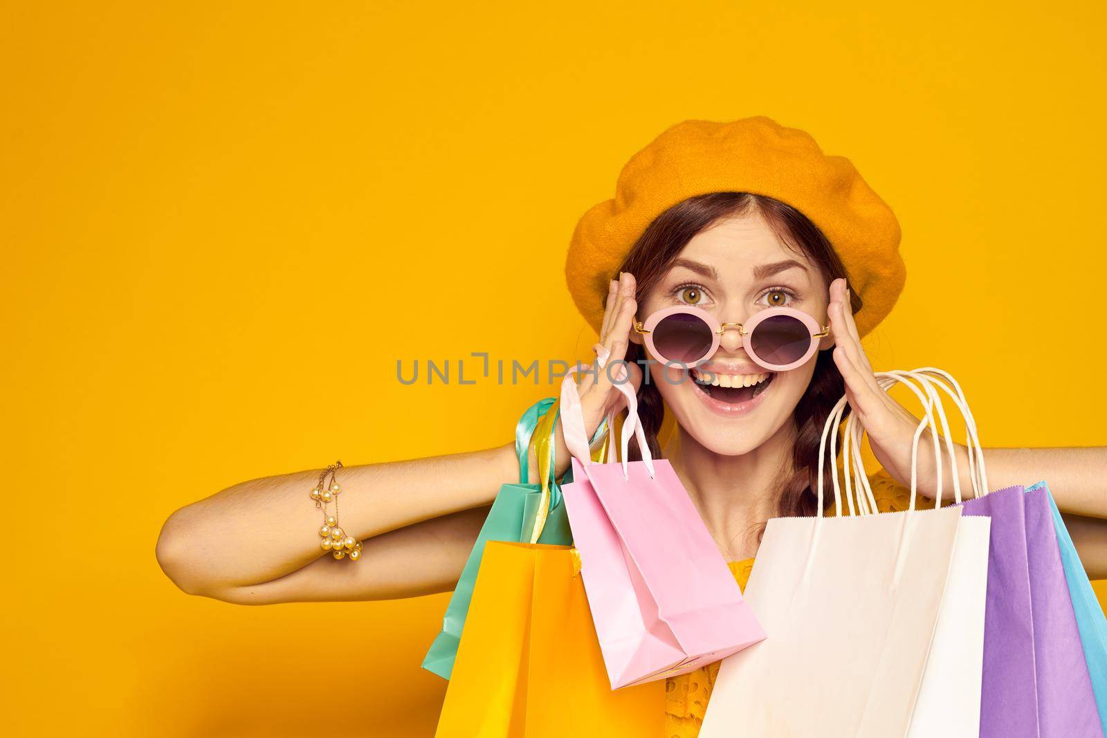 cheerful woman in a yellow hat Shopaholic fashion style studio model by Vichizh