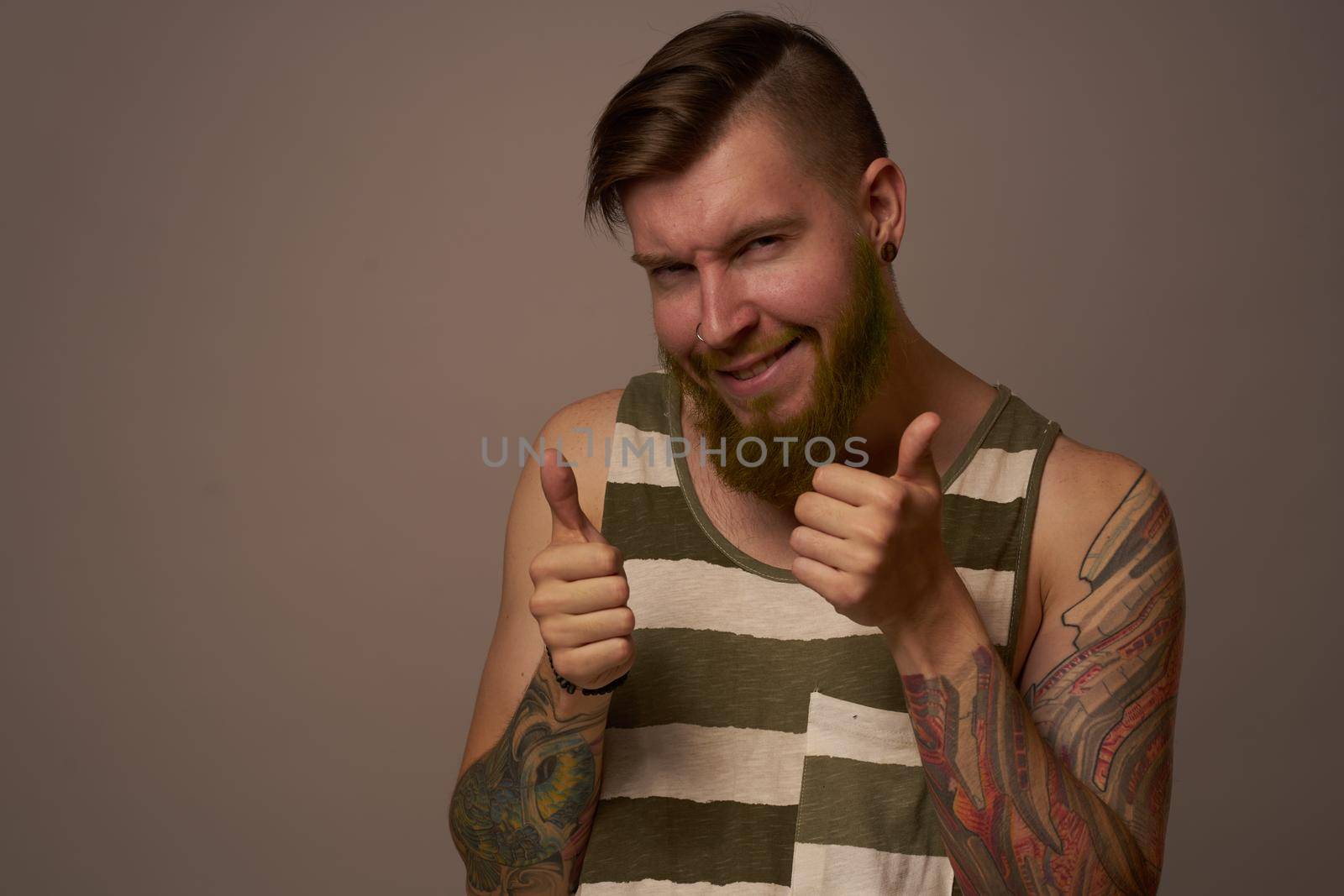 fashionable man with tattoos on his arms stylish hairstyle self-confidence studio by Vichizh