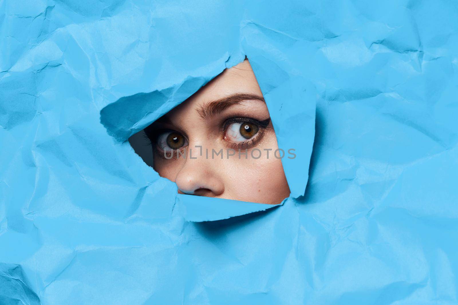 woman's face breaks through blue mockup close-up. High quality photo