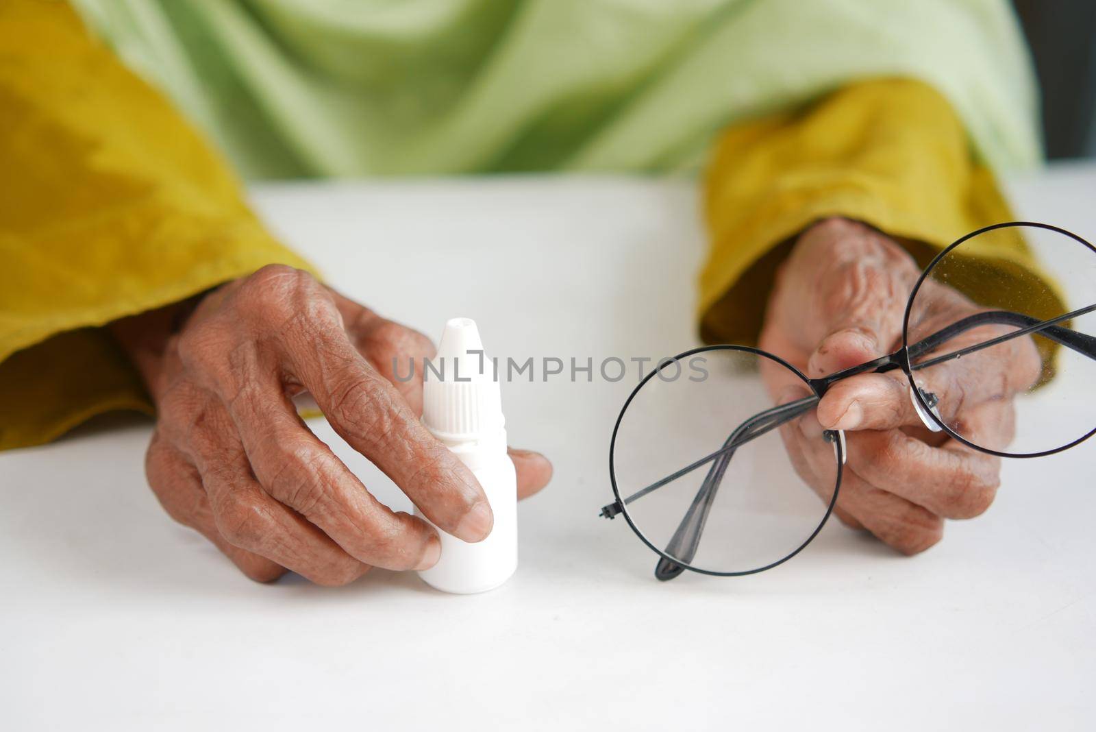 senior women hand holding a eye dropper on table .