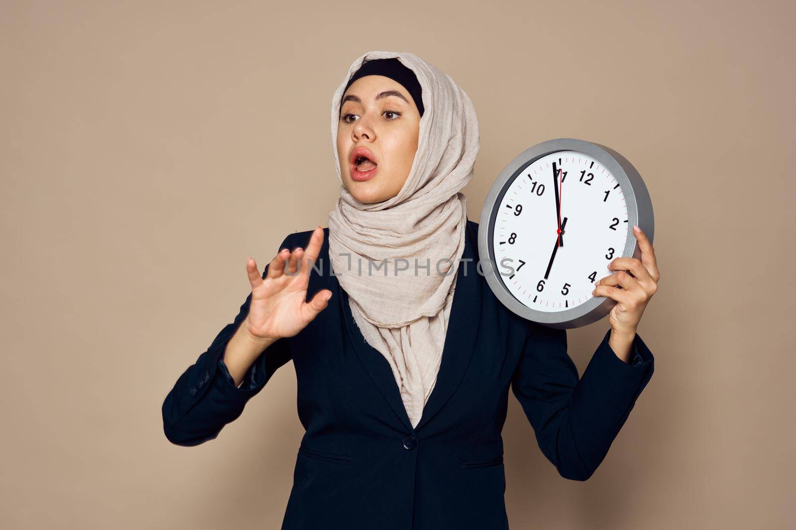 woman in hijab with clock in hands work office beige background by Vichizh