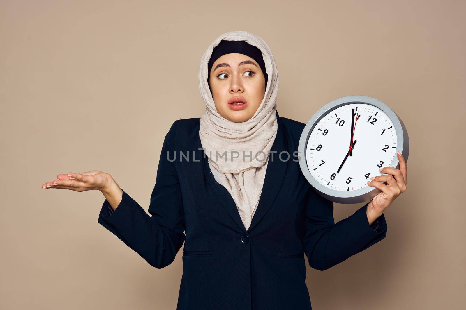 woman in hijab with clock in hands work office beige background by Vichizh