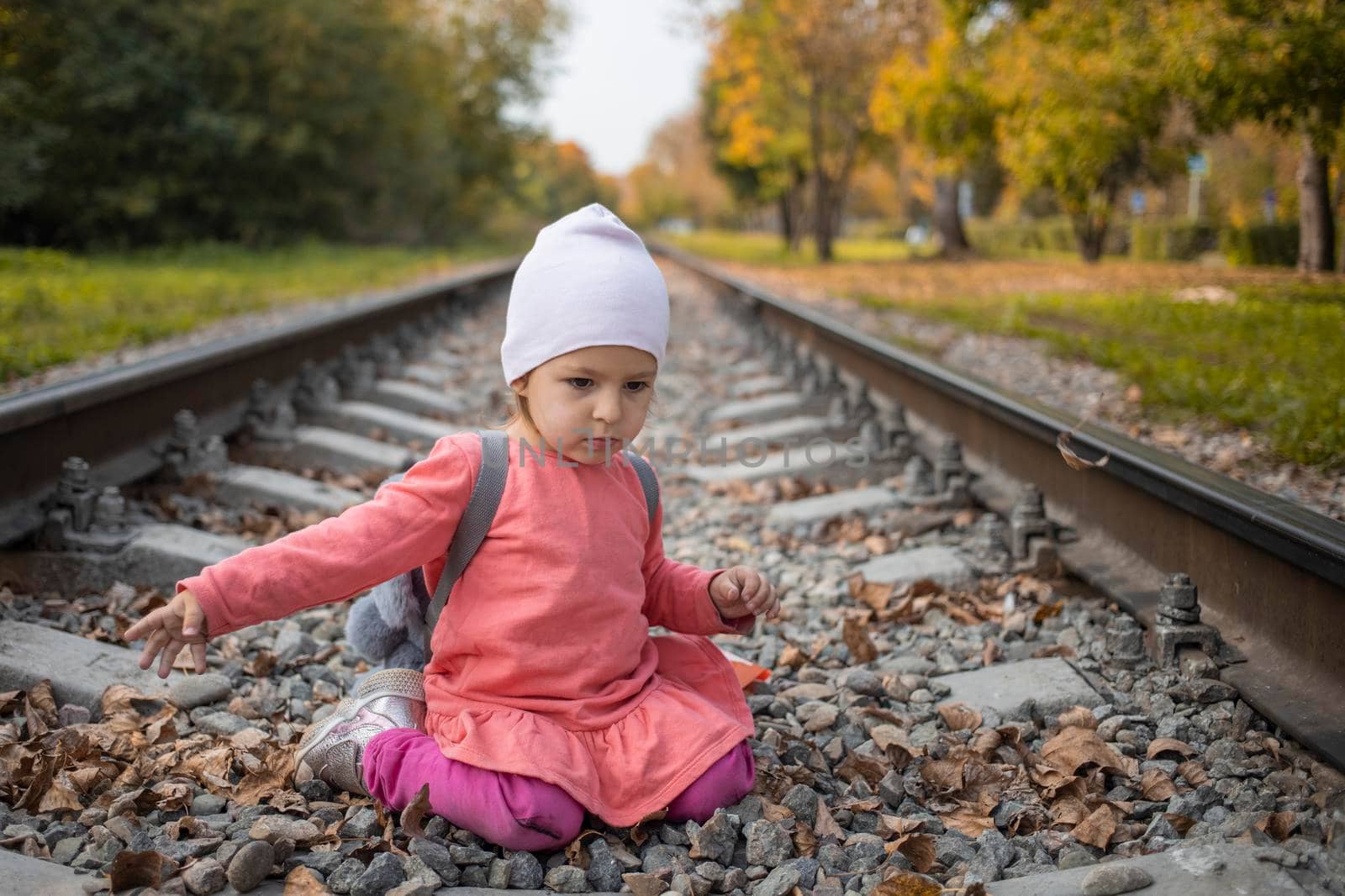 portrait of little girl sitting on the train tracks in the forest