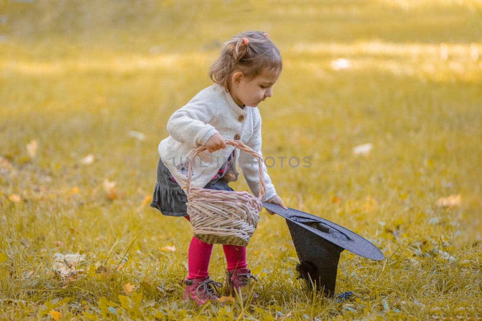 halloween concept. cute little girl playing with witch hat in autumn park.