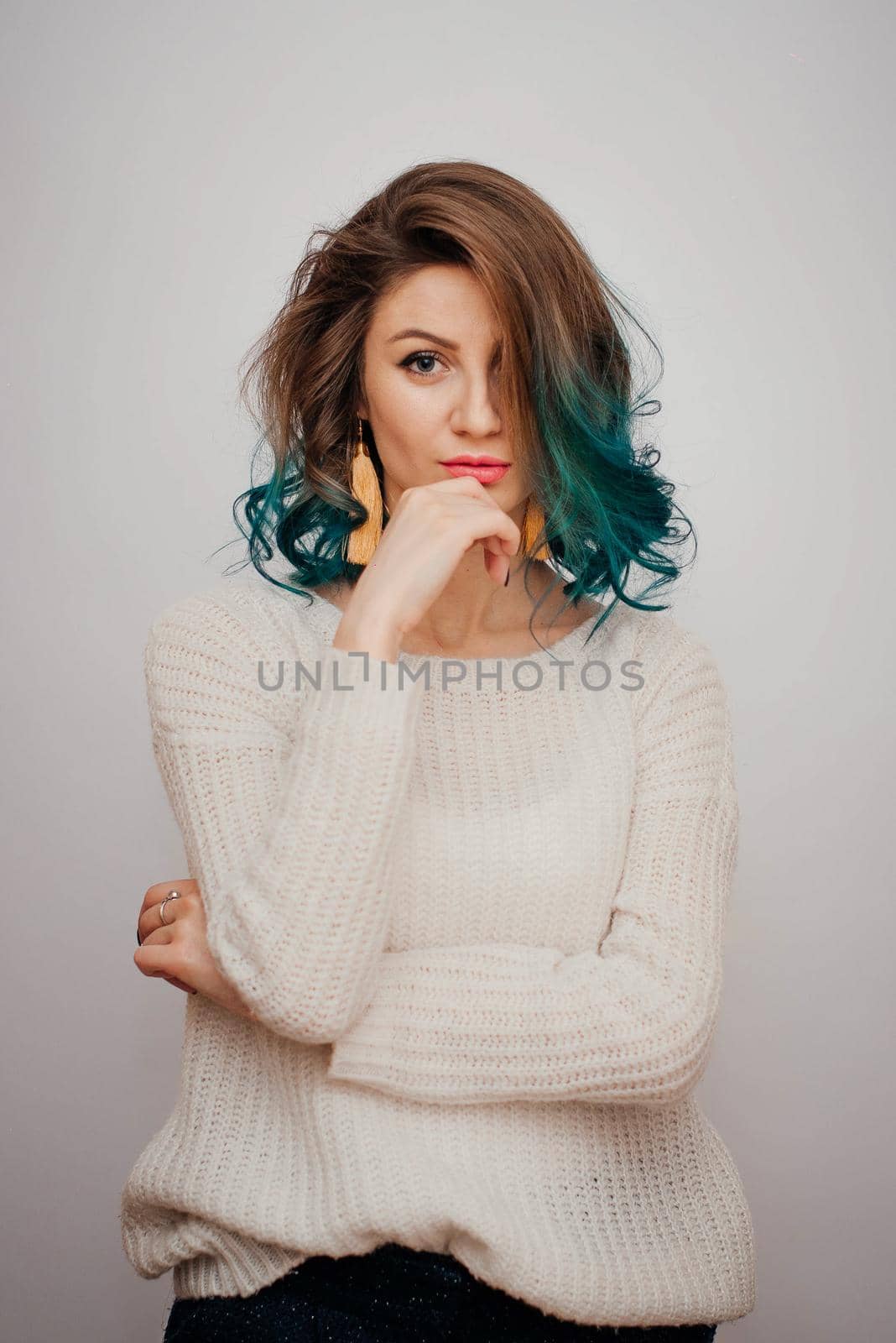 Pretty woman portrait with colored hair on a white background. Long yellow earrings in contrast with turquoise hair.