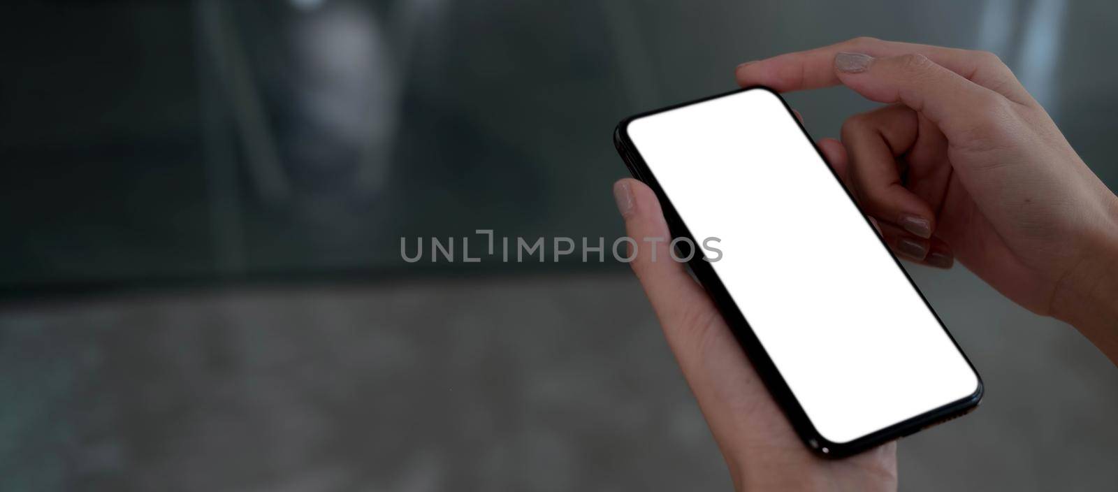Mockup image blank white screen cell phone.women hand holding texting using mobile on desk at home office...