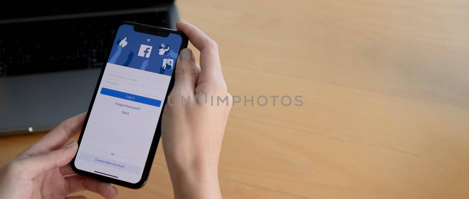 CHIANG MAI ,THAILAND AUG 18 2021 : Woman holding a iPhone X with social Internet service Facebook on the screen. by wichayada