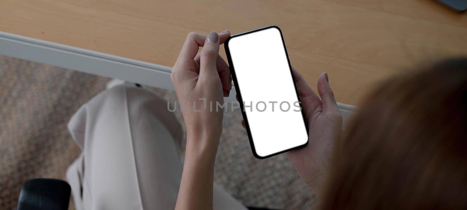 Mockup image blank white screen cell phone.women hand holding texting using mobile on desk at home office...