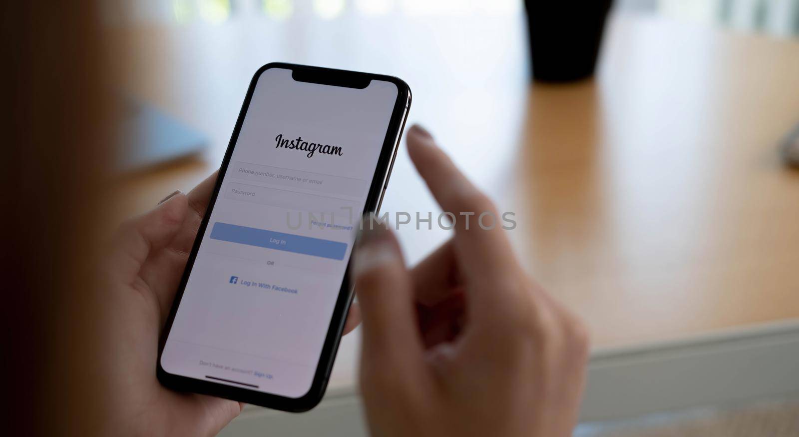 CHIANG MAI, THAILAND - AUG 26, 2021: A woman holds Apple iPhone X with Instagram application on the screen at cafe. Instagram is a photo-sharing app for smartphones...