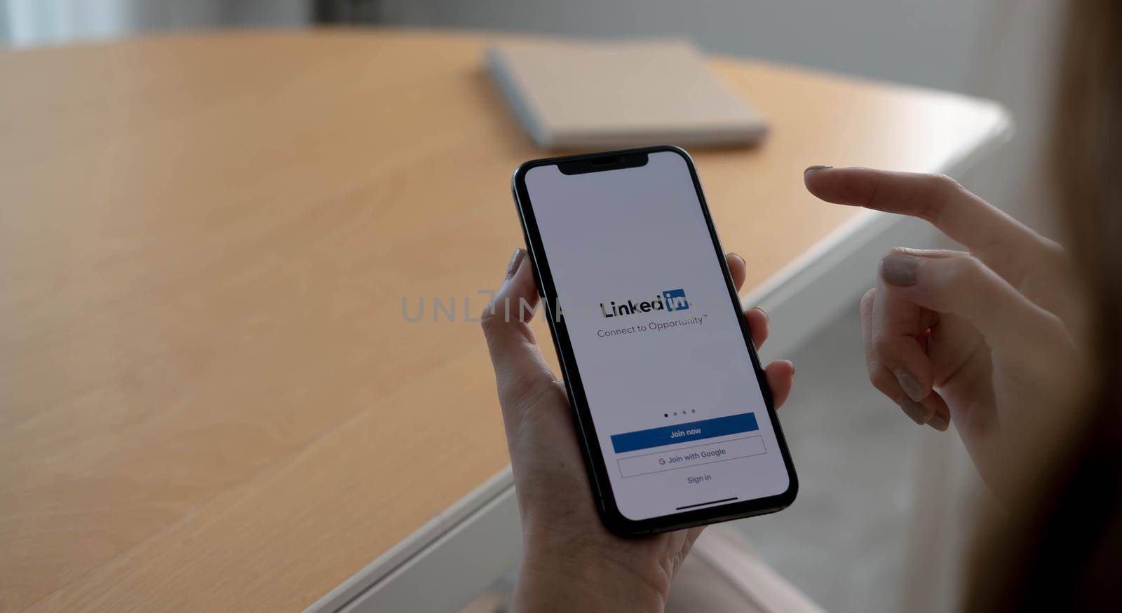 CHIANG MAI, THAILAND, OCT 12, 2021 : A women holds Apple iPhone Xs with LinkedIn application on the screen.LinkedIn is a photo-sharing app for smartphones...