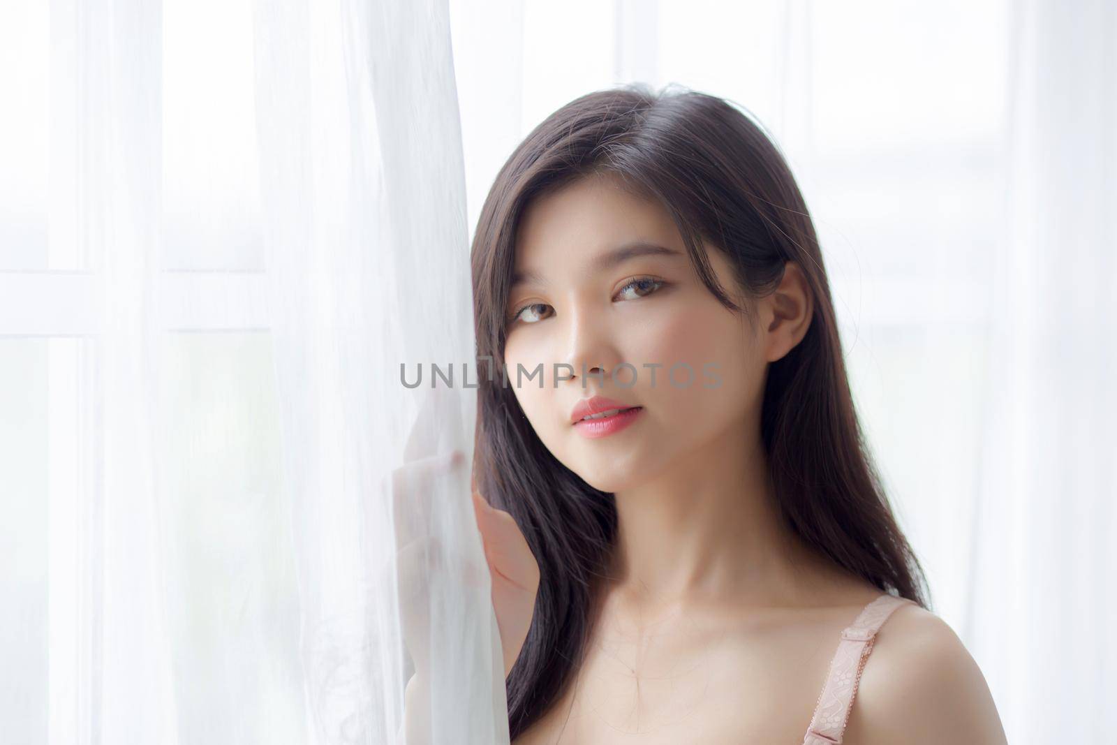 Beautiful portrait young asian woman sexy standing the window and smile while wake up with health, body of girl happy with freshness and cheerful with wellbeing, lifestyle and relax concept.