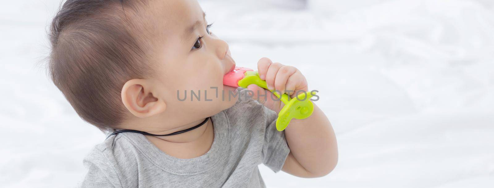 Portrait of cute little baby girl sitting with cozy on bed at bedroom, happiness of toddler, newborn 6-11 months with innocence and expression with cheerful, child charm, indoors, one person.