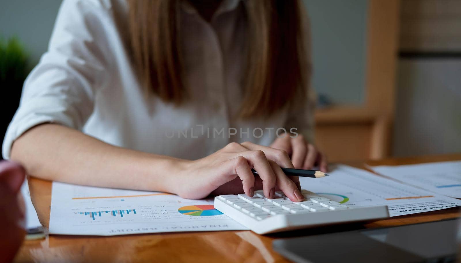 Close up Business woman using calculator and laptop for do math finance on wooden desk in office and business working background, tax, accounting, statistics and analytic research concept.