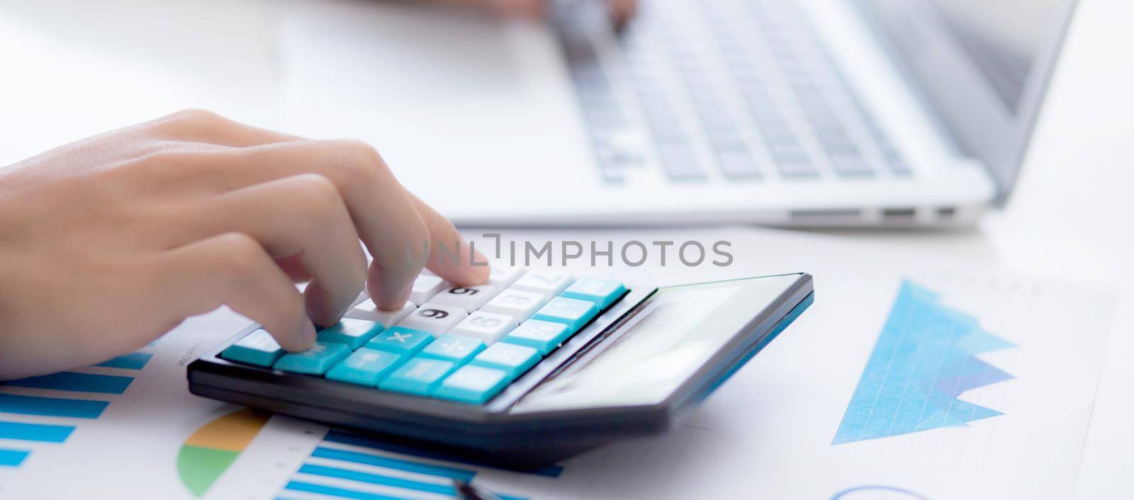 Hand of young asian business man working using calculator for planning accountant, graph for finance and report statistics, investment and profit of income, businessman analyzing with chart.