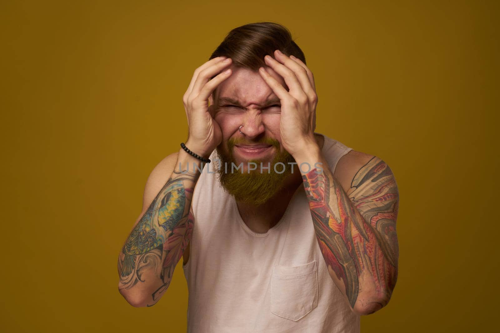 Cheerful bearded man in a white T-shirt with hooligan tattoos on his arms by Vichizh