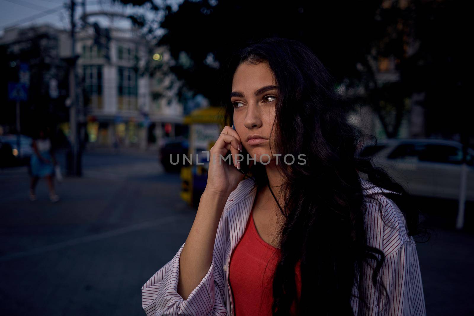 woman talking on the phone outdoors walking in the evening on the street. High quality photo