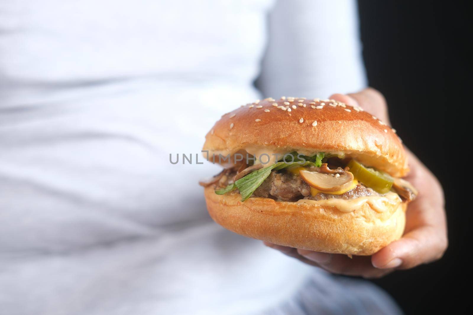 hand holding beef burger on table close up .