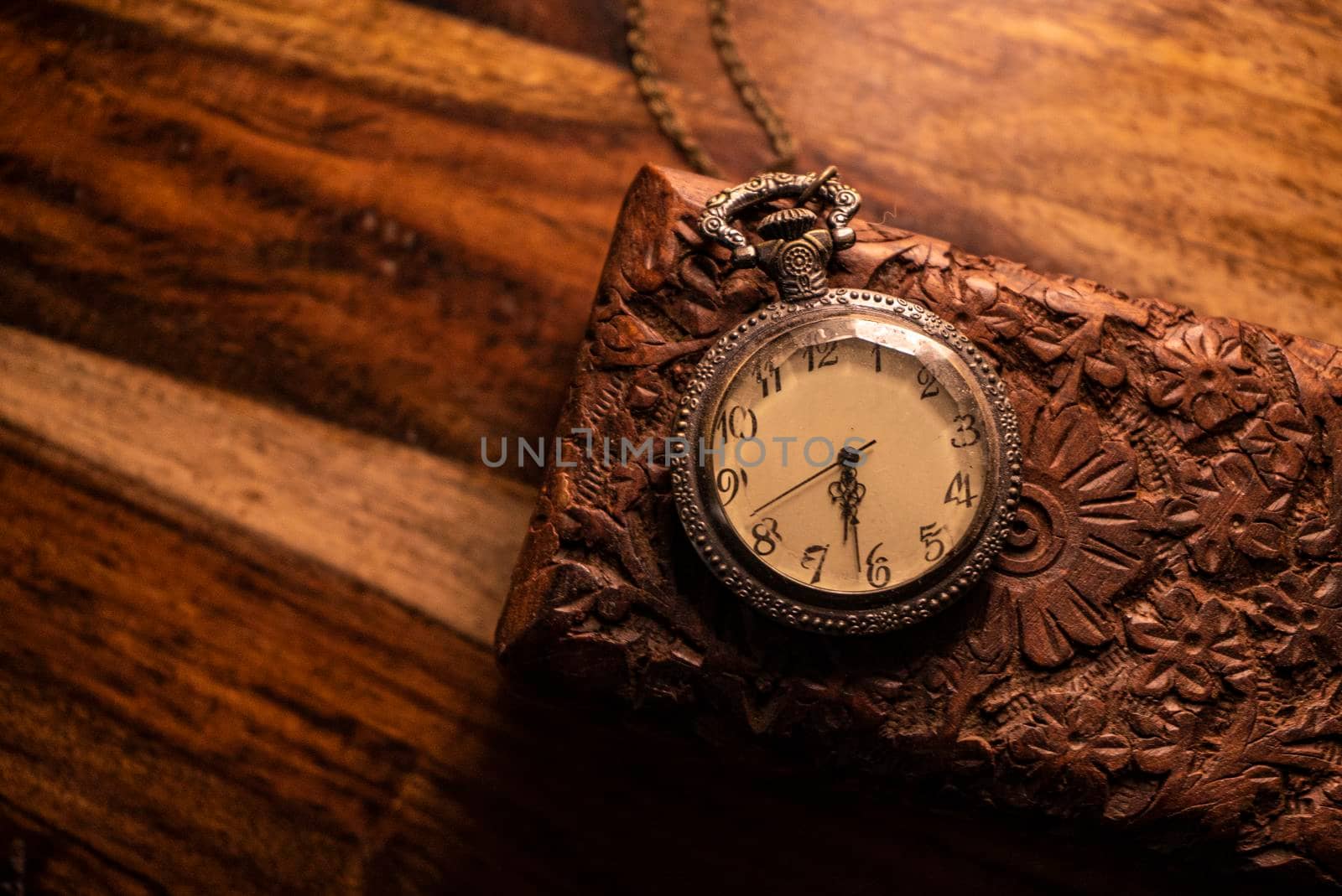 On the table are an old pocket watch over an ancient wooden case. Vintage background from a collection of antiques. Close-up and selected focus