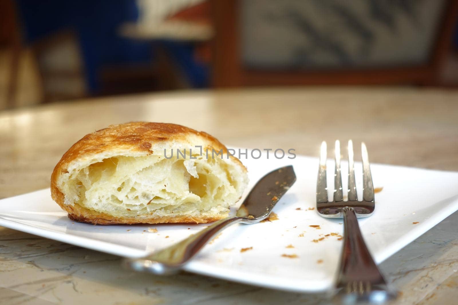 half eaten fresh baked croissant on cafe table .