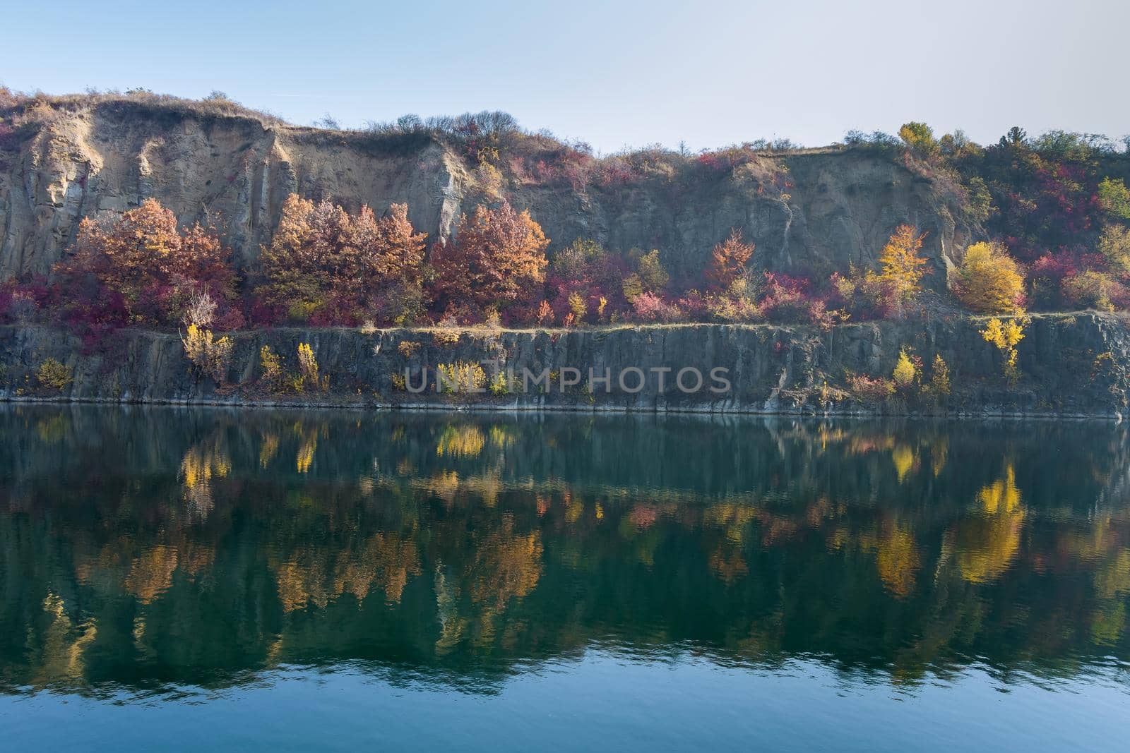 View of the artificial lake in a flooded part of a granite quarry lined with stone by ungvar