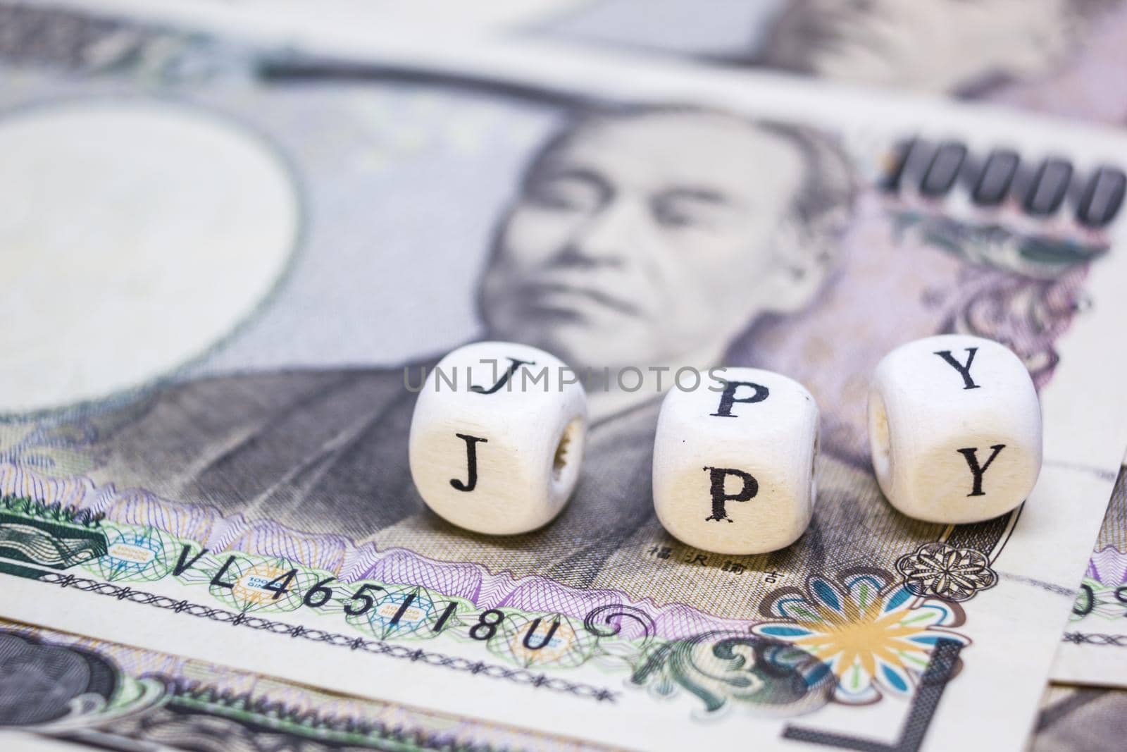 close-up of wooden cube with text "J P Y" on banknote YEN for business and financial concept. by rakoptonLPN