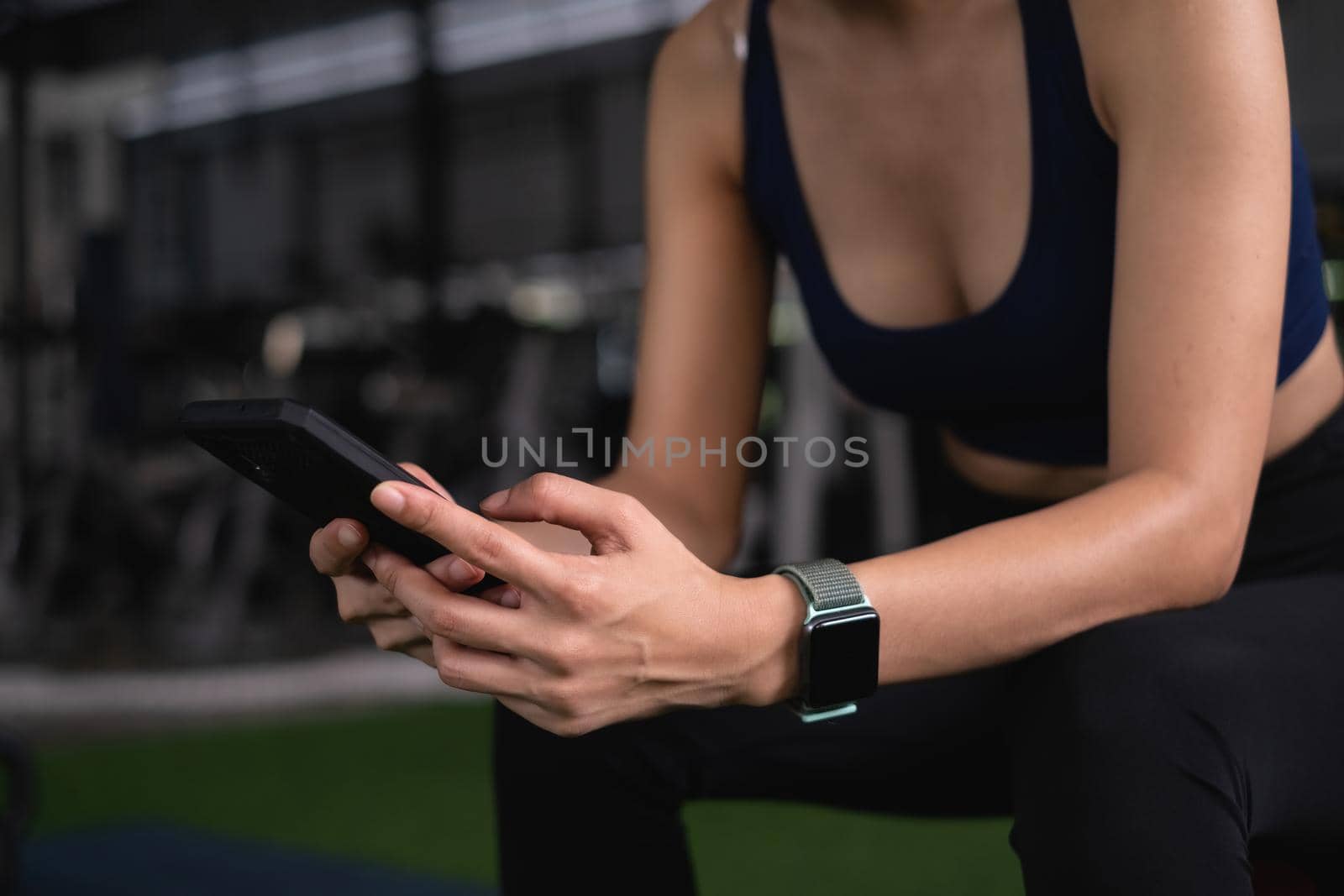 Beautiful sporty woman using phone checking her work before sports training at gym