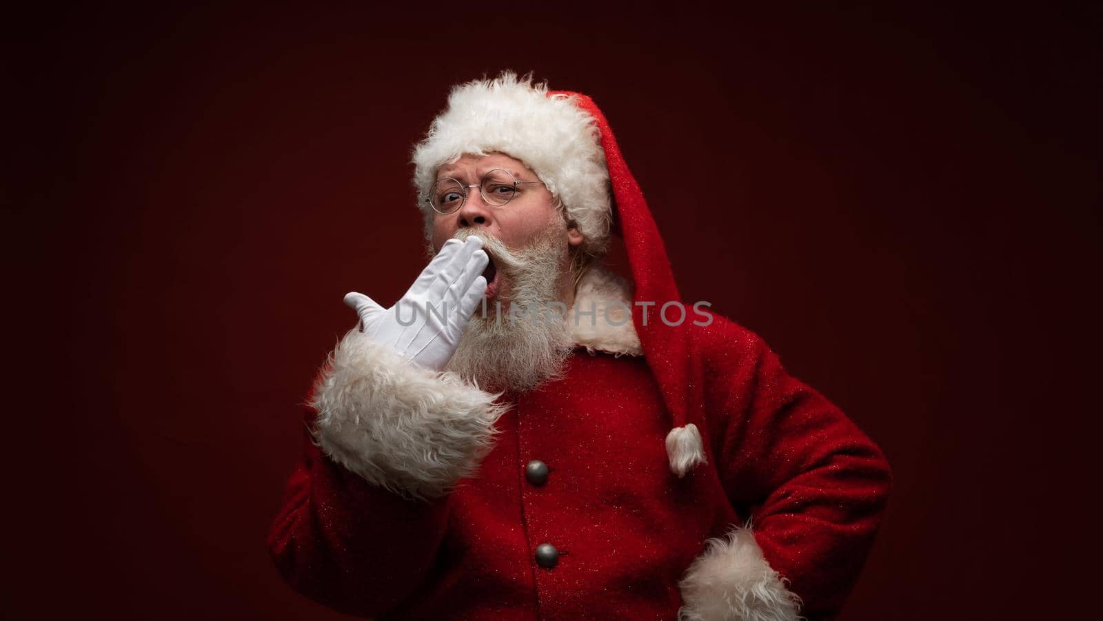 Sleepy Santa Claus yawning, wearing glasses and hat.