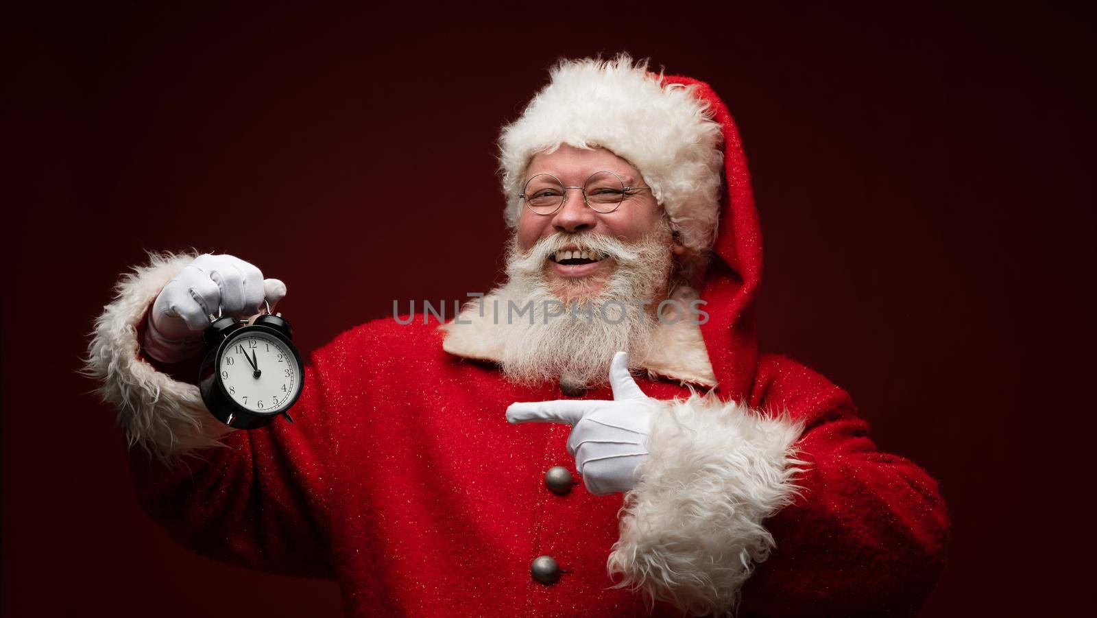 Santa claus pointing at alarm clock almost midnight