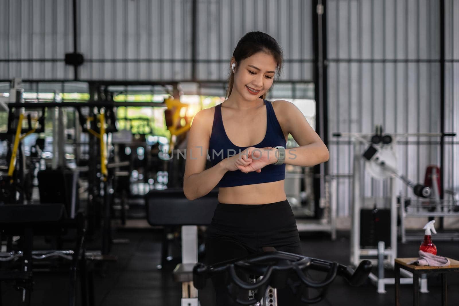 Beautiful sporty woman using smart watch checking notify between sports training at gym.