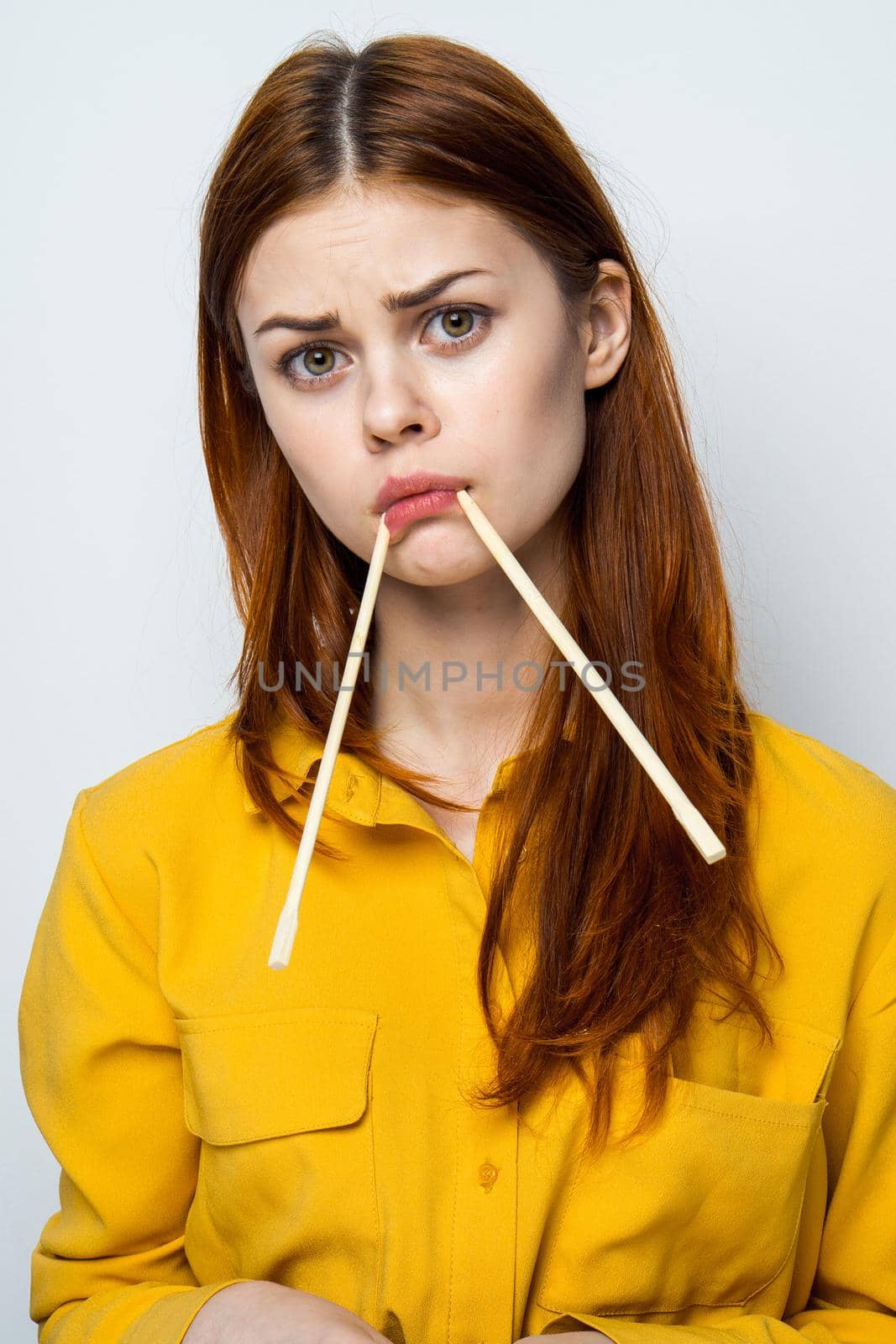 woman eating sushi with japanese chopsticks posing light background. High quality photo