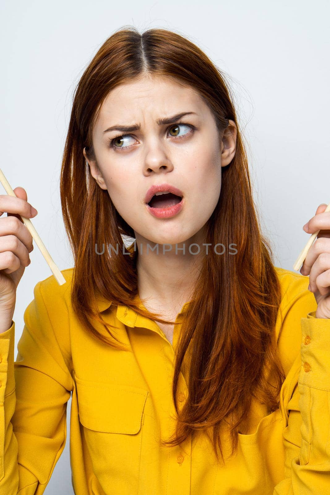 woman eating sushi with japanese chopsticks posing light background by Vichizh