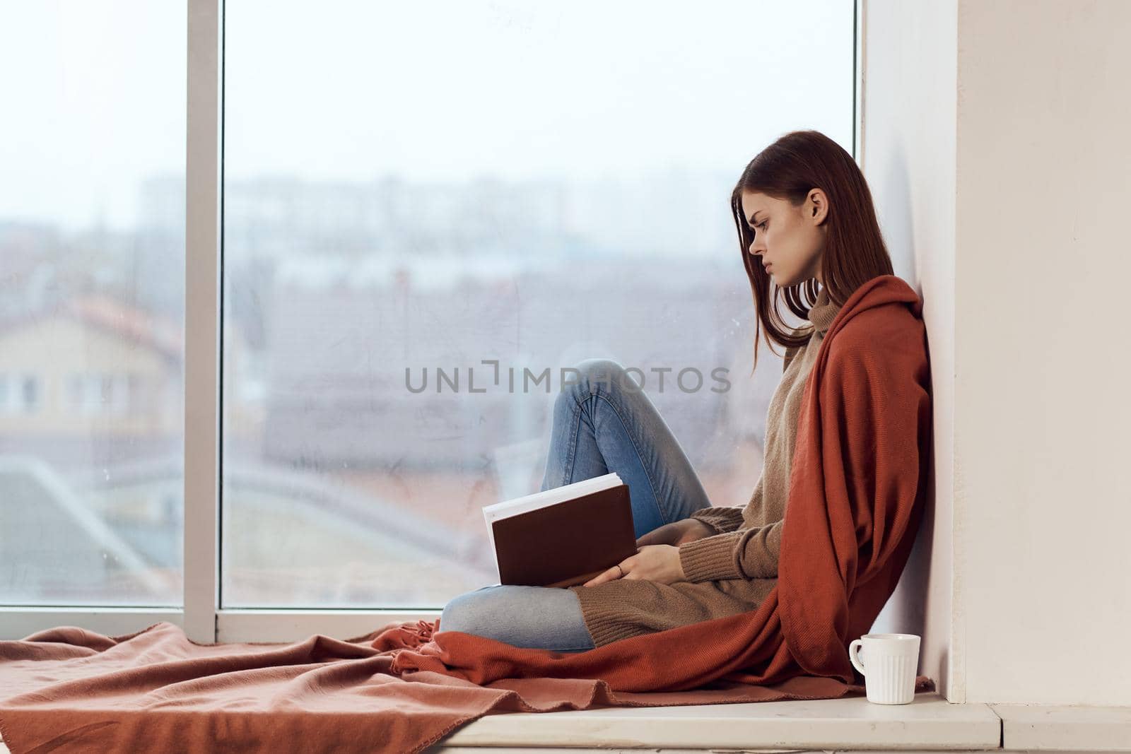 woman with a book near the window with a cup of coffee. High quality photo