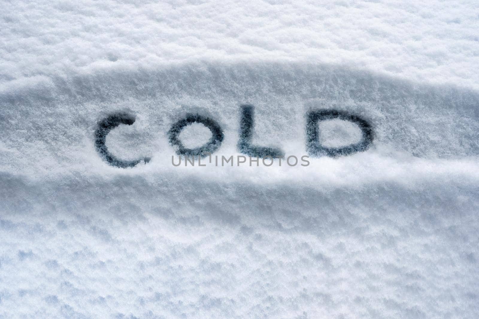 Written white snow cold weather concept. Winter cover snow weather conditions. Snowy winter cold temperature background. Written word COLD symbol. Bad weather warning. Below zero forecast snow concept