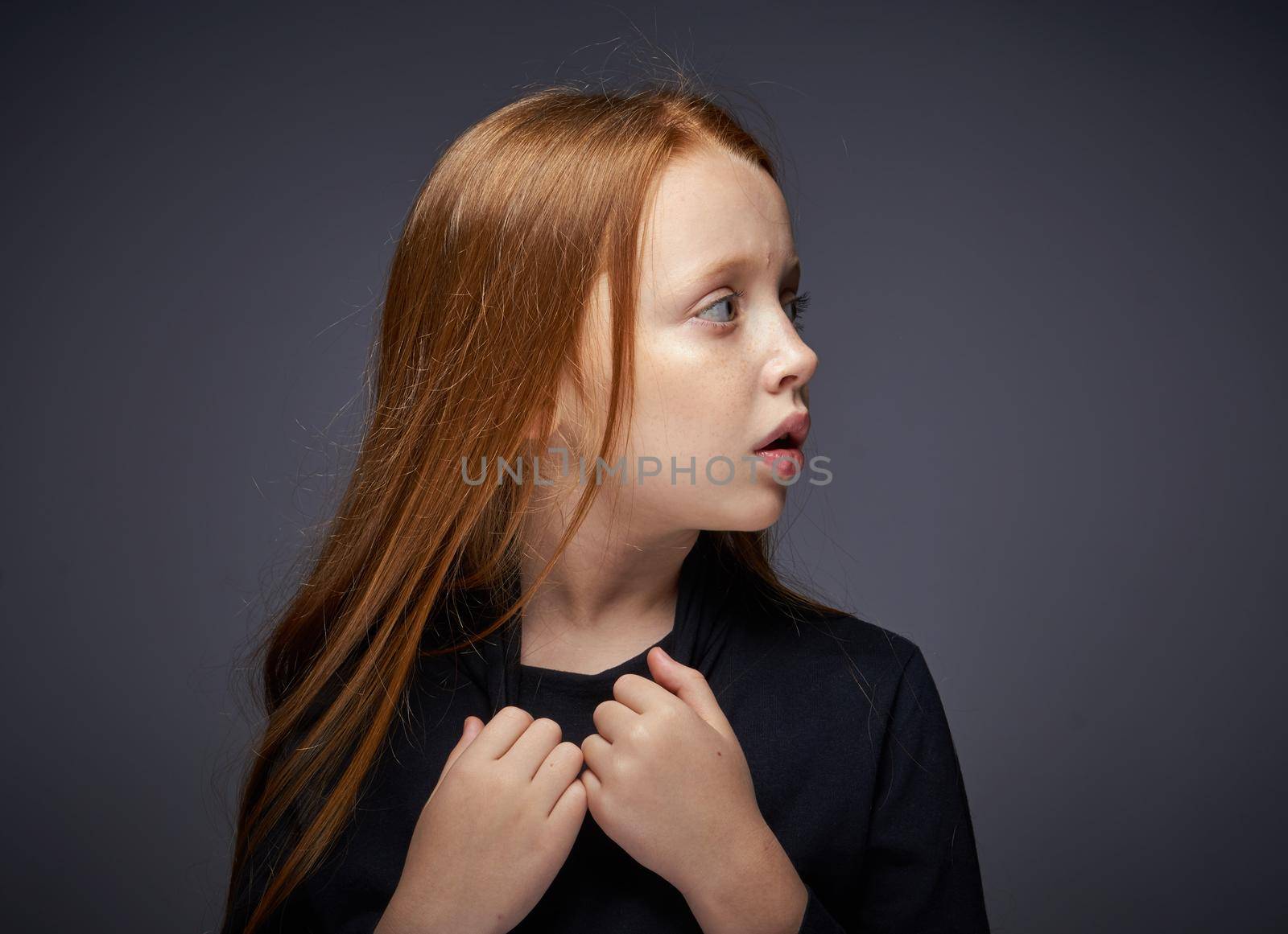red-haired girl with freckles on her face in a black sweater posing. High quality photo