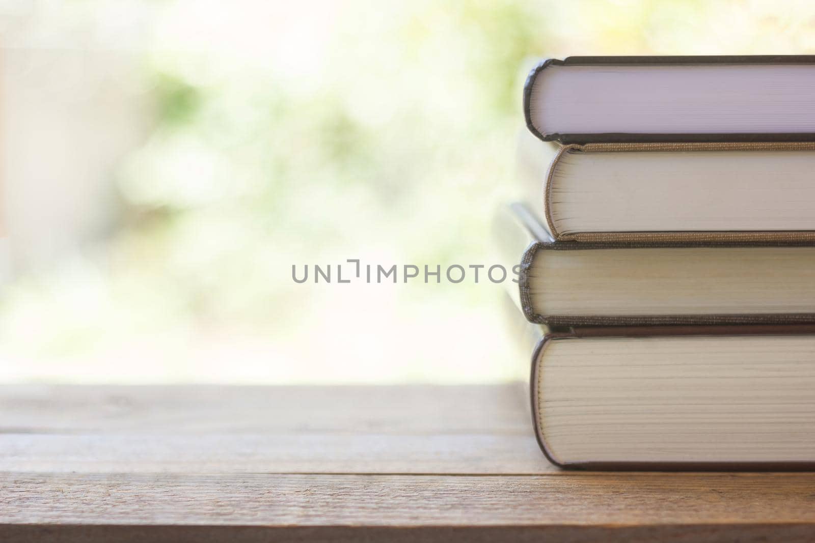 stack of thick books with green light and bokeh background by rakoptonLPN