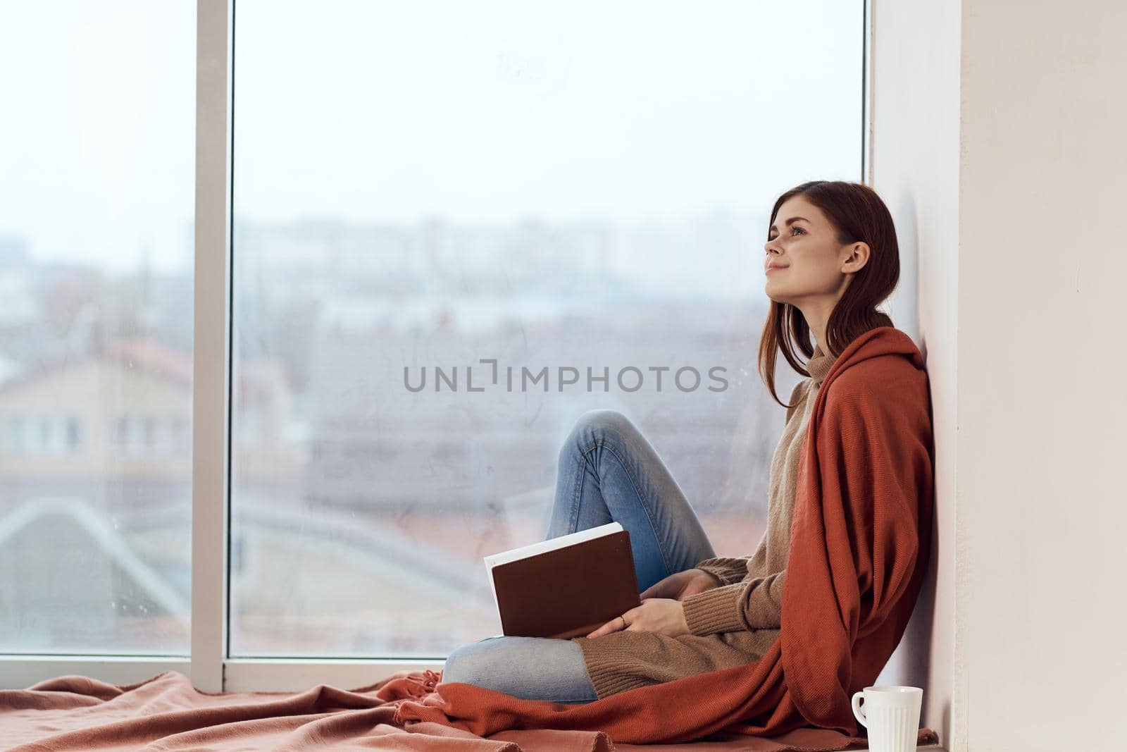 woman with a book near the window with a cup of coffee. High quality photo