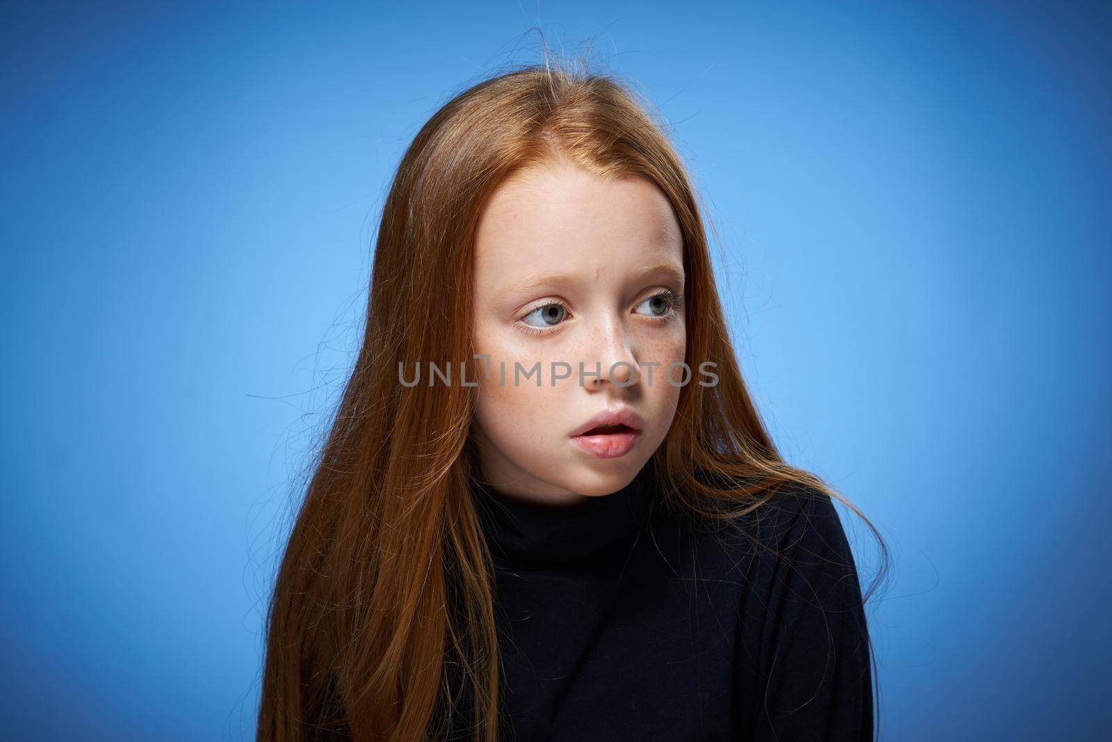 redhead girl with freckles on her face posing close-up blue background. High quality photo