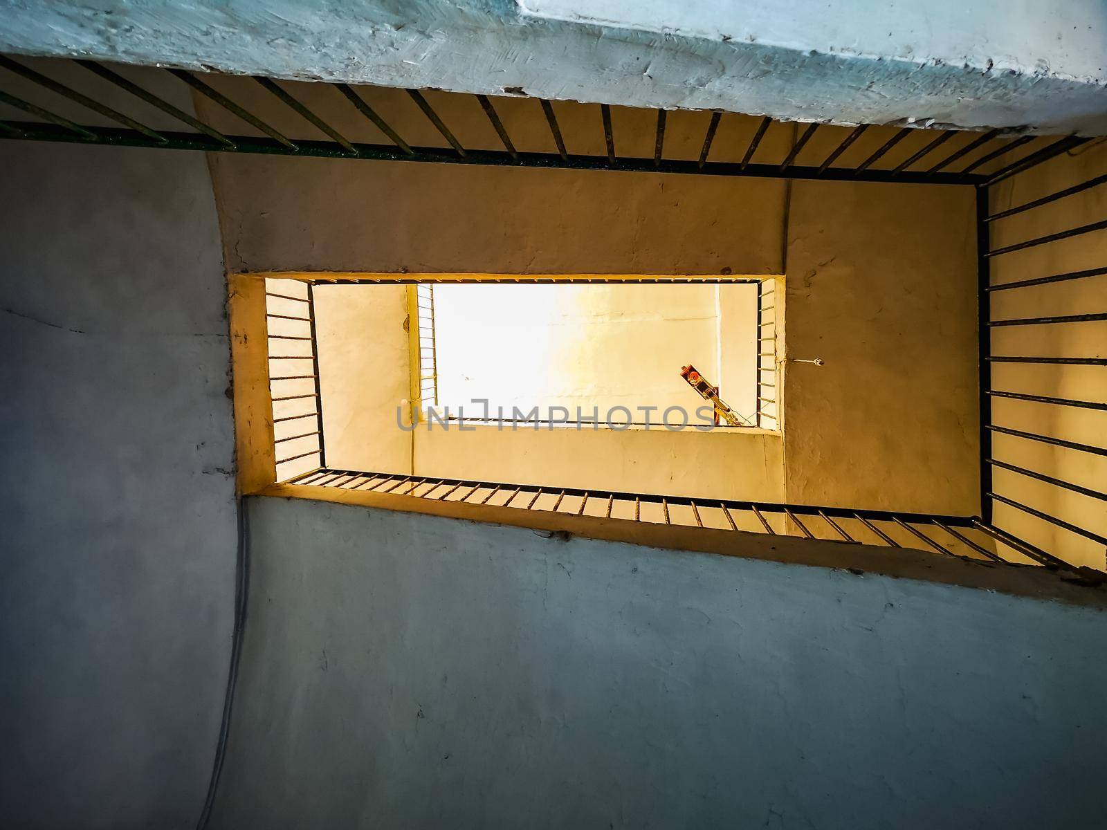 Upward view to spiral square staircase in old tenement house on Capri island