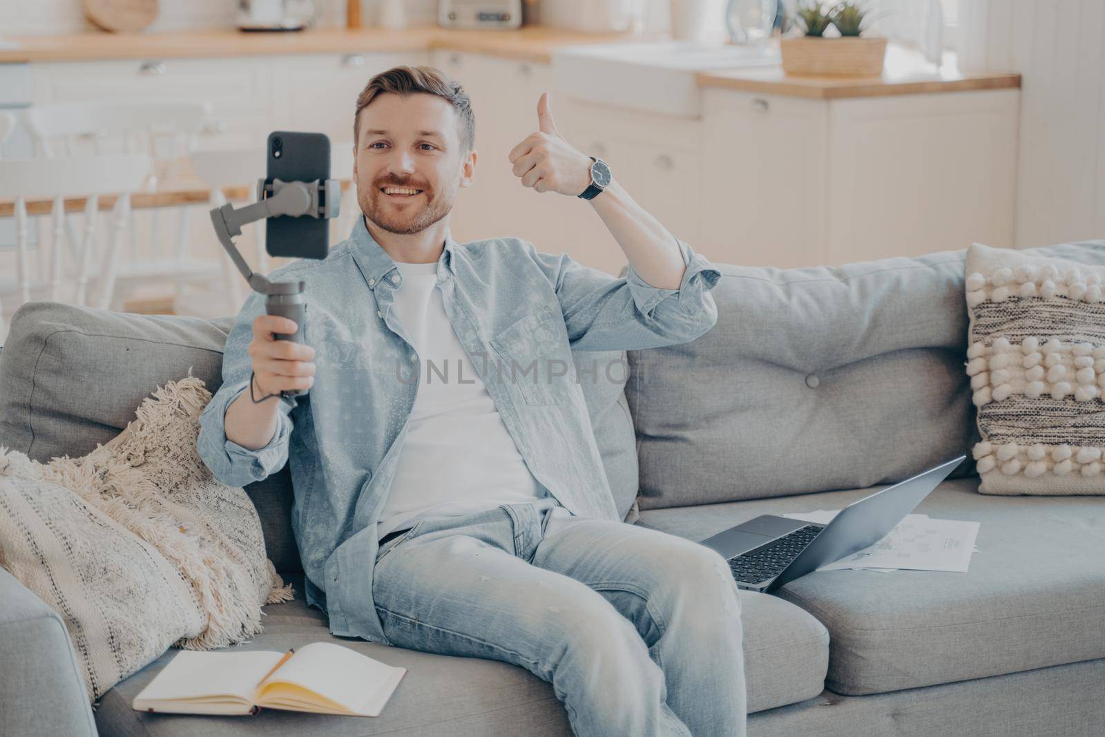 Confident young male freelancer showing thumbs up gesture to his client in video call by vkstock