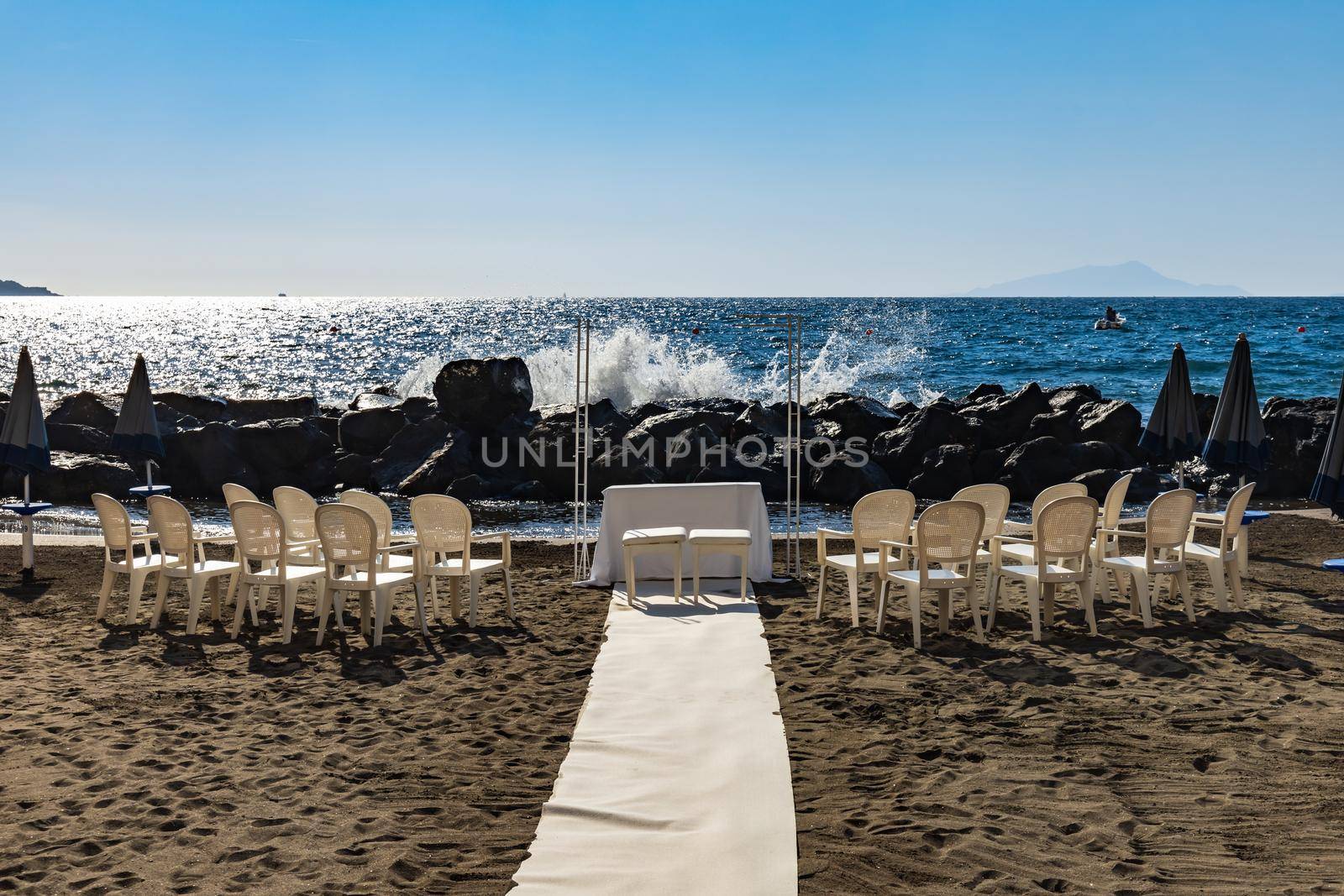 Preparations of wedding party on small beach next to sea and big rocks