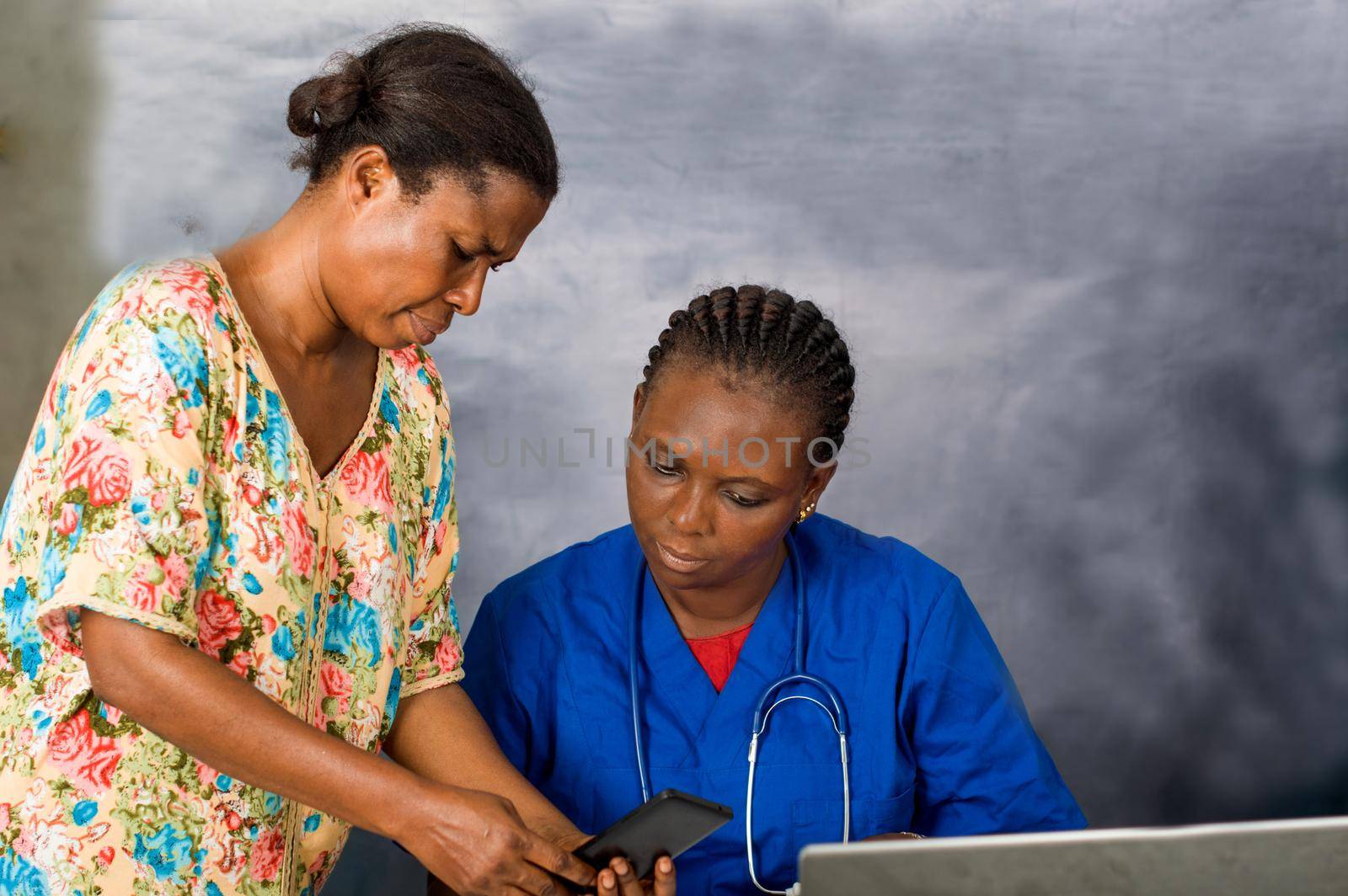 Mature doctor and african surgeon working on digital tablet with nurse.