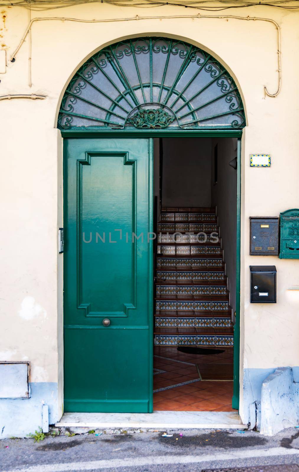 Large green doors with arc window over it as entrance to old tenement house