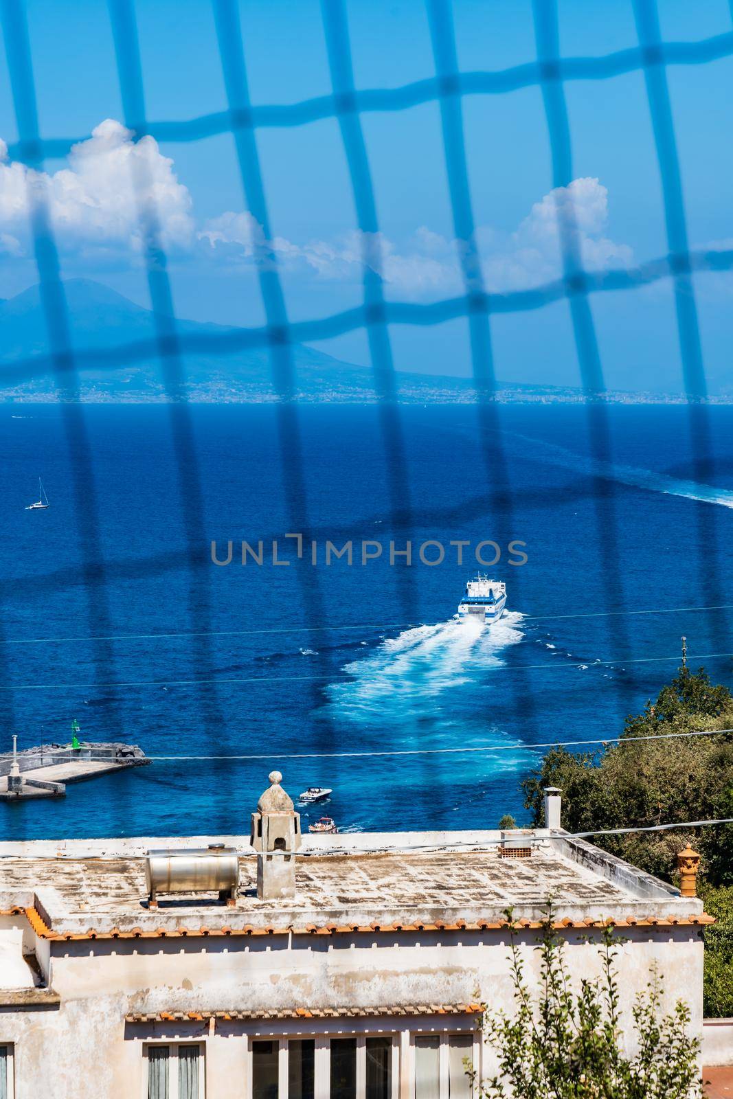 Small boat swimming on the sea seen through small metal net